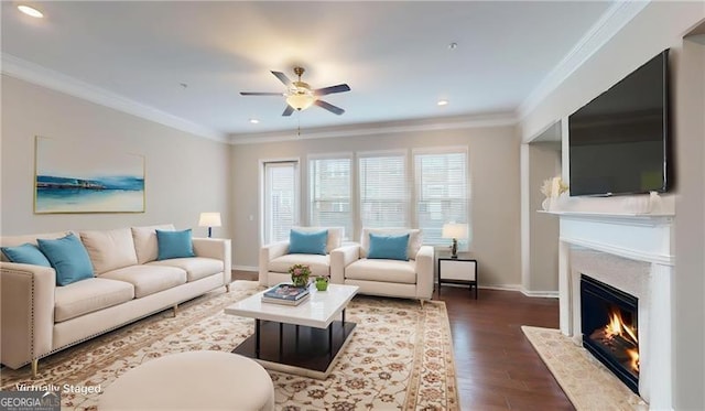 living area with ceiling fan, dark wood-style floors, baseboards, a high end fireplace, and ornamental molding