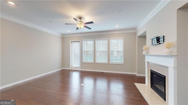 unfurnished living room with a high end fireplace, a ceiling fan, dark wood-style flooring, crown molding, and baseboards
