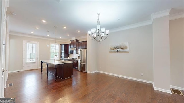 kitchen with stainless steel fridge, a chandelier, a kitchen island with sink, dark brown cabinets, and light countertops