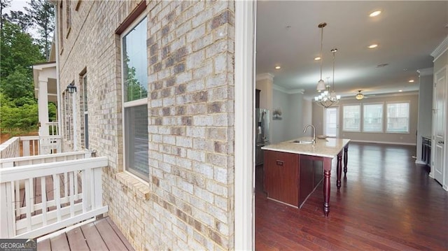 kitchen featuring crown molding, a sink, dark wood-type flooring, open floor plan, and a kitchen island with sink