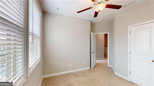 unfurnished bedroom with light colored carpet, baseboards, and ceiling fan