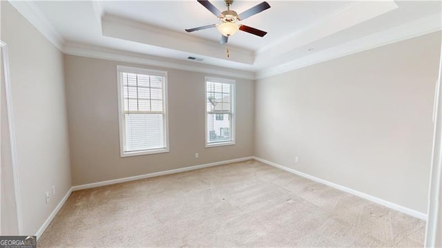 unfurnished room with crown molding, a tray ceiling, light colored carpet, a ceiling fan, and baseboards