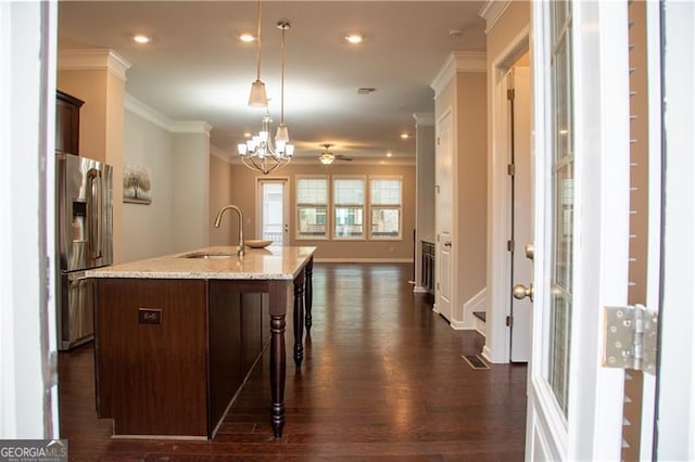 kitchen featuring stainless steel fridge, a sink, ornamental molding, dark wood-type flooring, and a kitchen breakfast bar