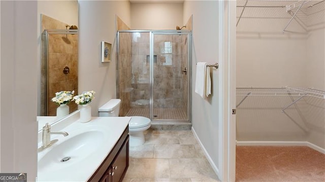 bathroom with a stall shower, toilet, vanity, baseboards, and a spacious closet