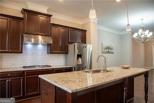 kitchen with appliances with stainless steel finishes, under cabinet range hood, a sink, tasteful backsplash, and light stone countertops