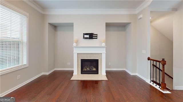 unfurnished living room with wood finished floors, ornamental molding, a glass covered fireplace, and baseboards