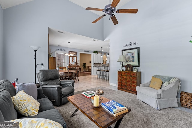 living room with high vaulted ceiling, ceiling fan with notable chandelier, light tile patterned flooring, and visible vents