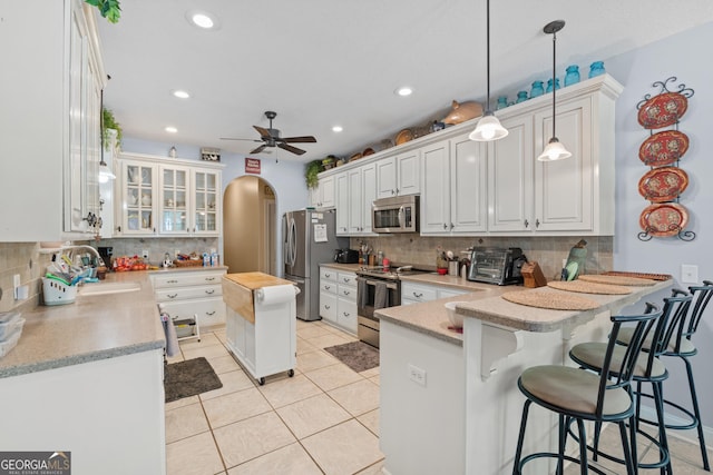 kitchen featuring a sink, appliances with stainless steel finishes, decorative backsplash, and a peninsula