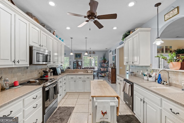 kitchen featuring decorative backsplash, a ceiling fan, white cabinets, a sink, and stainless steel appliances
