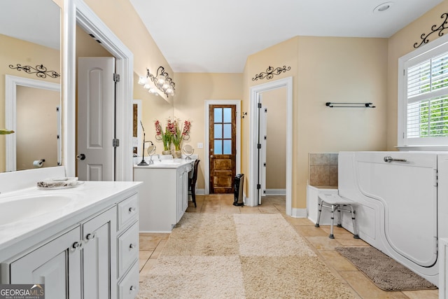 full bath with a sink, tile patterned floors, baseboards, and two vanities