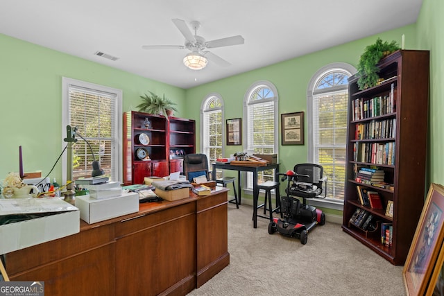 home office featuring visible vents, ceiling fan, and light colored carpet