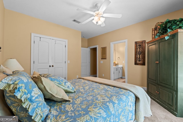 bedroom with a ceiling fan, light colored carpet, visible vents, a closet, and ensuite bath