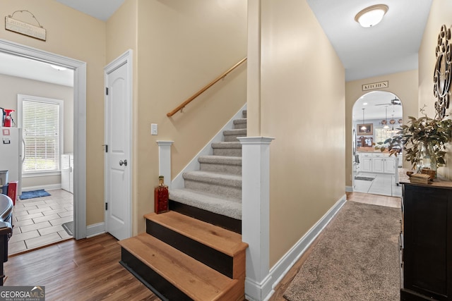 interior space with baseboards, arched walkways, and wood finished floors