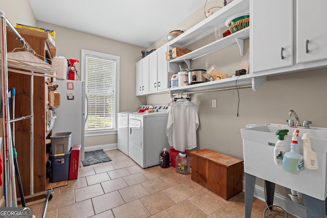 laundry room with cabinet space, light tile patterned floors, baseboards, a sink, and washer and clothes dryer