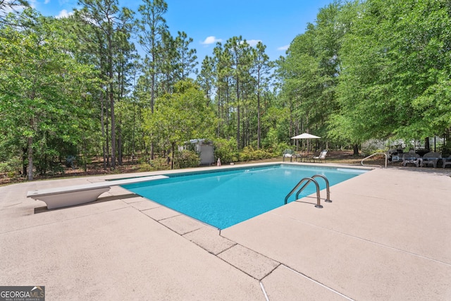 outdoor pool featuring a patio and a diving board