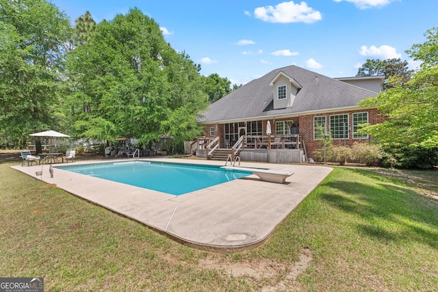 outdoor pool featuring a lawn, a deck, a patio, and a diving board