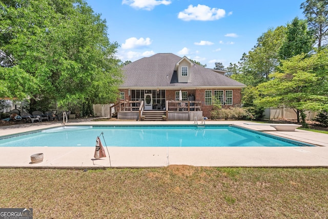view of pool featuring a deck, a diving board, a fenced in pool, fence, and a yard