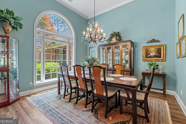 dining room with baseboards, ornamental molding, wood finished floors, and a high ceiling