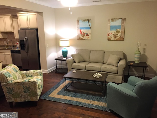 living area featuring a ceiling fan, visible vents, baseboards, ornamental molding, and dark wood-type flooring