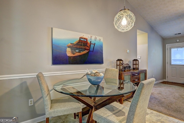 dining room with visible vents, a textured ceiling, baseboards, and vaulted ceiling