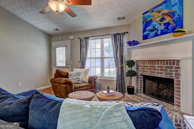 living room with visible vents, a textured ceiling, ceiling fan, and a fireplace