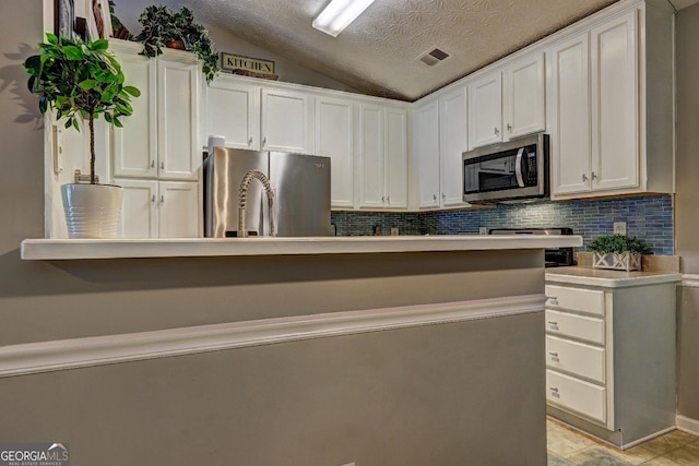 kitchen featuring decorative backsplash, visible vents, appliances with stainless steel finishes, vaulted ceiling, and white cabinets