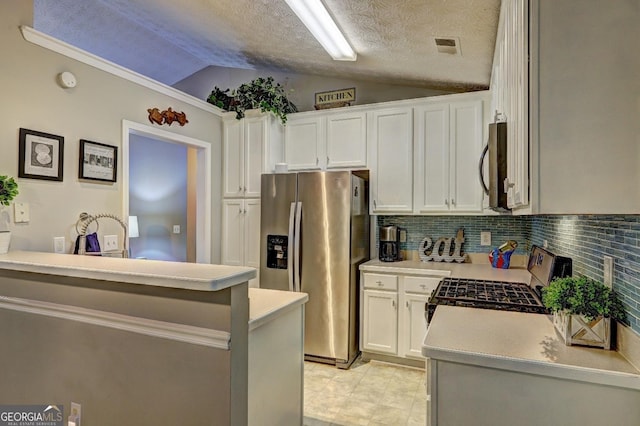 kitchen with decorative backsplash, light countertops, white cabinets, appliances with stainless steel finishes, and vaulted ceiling