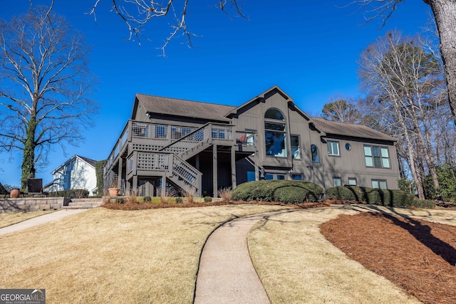 view of front of home featuring stairway, a wooden deck, and a shingled roof