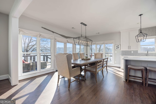 dining area featuring baseboards, an inviting chandelier, and dark wood-type flooring