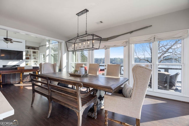 dining room featuring ceiling fan with notable chandelier and dark wood-style floors