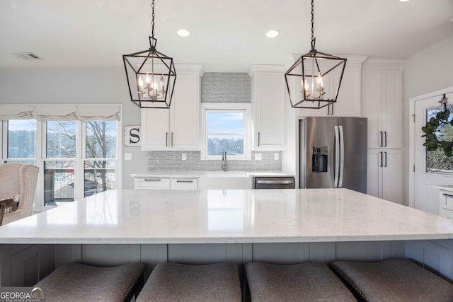 kitchen featuring white cabinetry, a notable chandelier, appliances with stainless steel finishes, and a sink