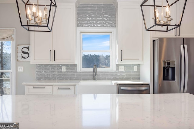 kitchen featuring a sink, backsplash, a notable chandelier, and appliances with stainless steel finishes