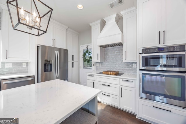 302 Odom Dr, Hamilton, GA 31811 - kitchen featuring appliances with stainless steel finishes, custom range hood, a chandelier, decorative backsplash, and white cabinets