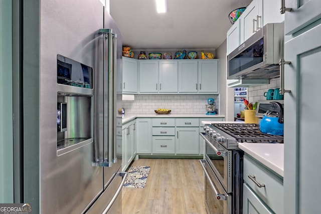 kitchen featuring high end appliances, light countertops, backsplash, and light wood finished floors