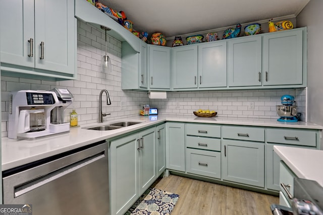 kitchen with stainless steel dishwasher, a sink, light countertops, light wood finished floors, and backsplash