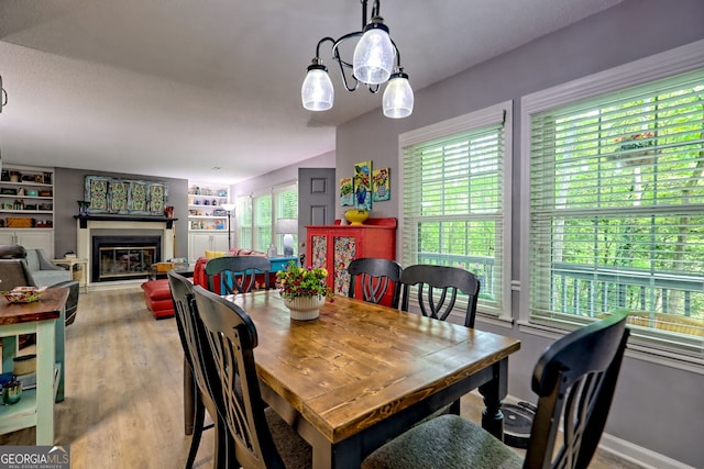 dining area featuring a glass covered fireplace, wood finished floors, and built in features