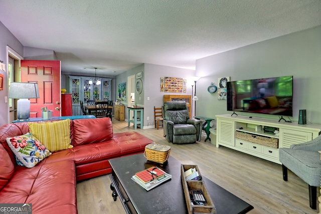 living area with wood finished floors, a textured ceiling, a chandelier, and baseboards
