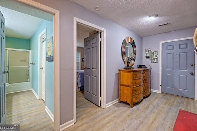 entryway with light wood-style flooring, a textured ceiling, and baseboards