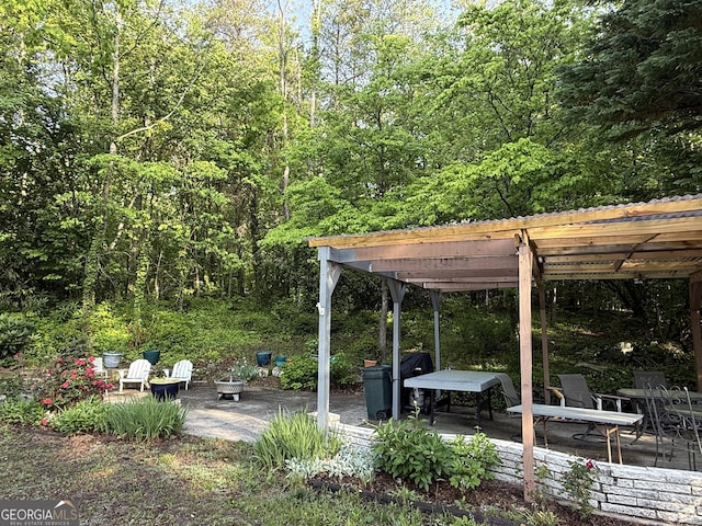 view of patio with a pergola and a view of trees