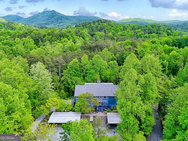 view of subject property with a heavily wooded area and a mountain backdrop