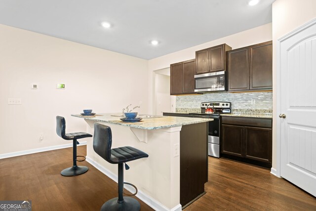 138 Yonah Way, Dallas, GA 30132 - kitchen featuring stainless steel appliances, dark wood-style floors, a center island with sink, a kitchen breakfast bar, and recessed lighting