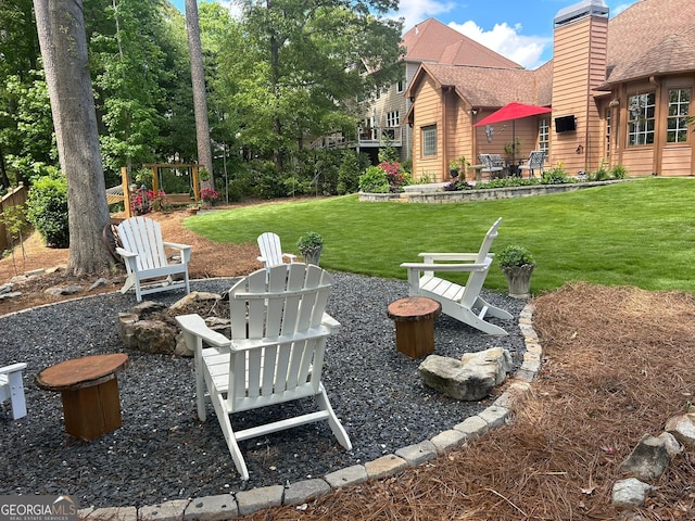 view of green lawn with a patio and an outdoor fire pit