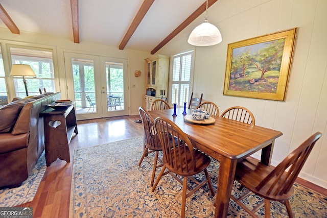 dining area featuring a healthy amount of sunlight, a decorative wall, french doors, and wood finished floors