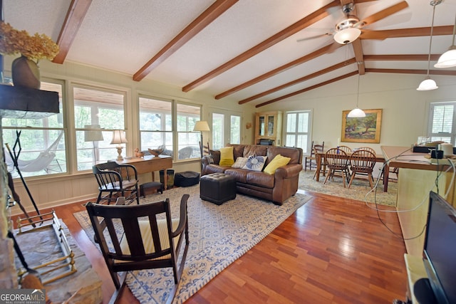 living room featuring vaulted ceiling with beams, a ceiling fan, and wood finished floors
