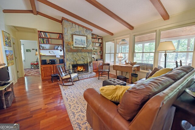 living room with a stone fireplace, lofted ceiling with beams, and wood finished floors