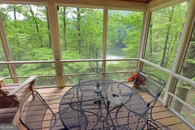 sunroom featuring a water view and outdoor dining space