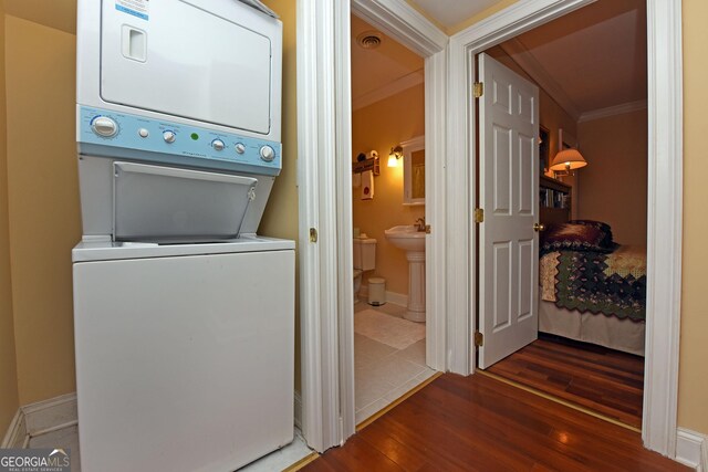 washroom featuring laundry area, visible vents, crown molding, stacked washer and clothes dryer, and dark wood-type flooring