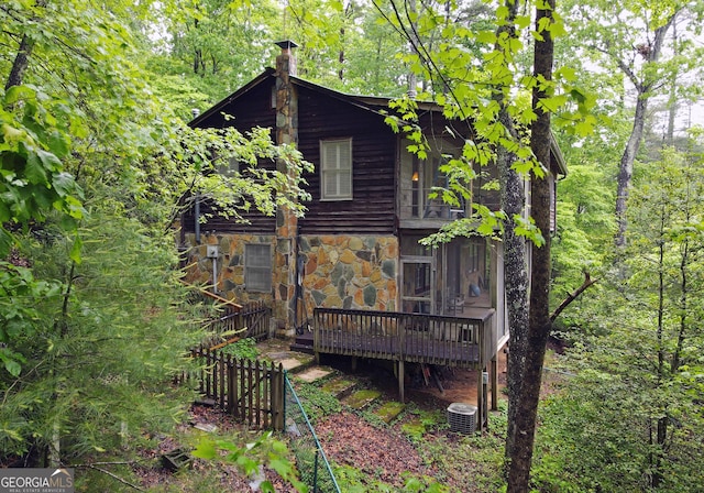 view of property exterior with a wooden deck, central AC unit, and stone siding