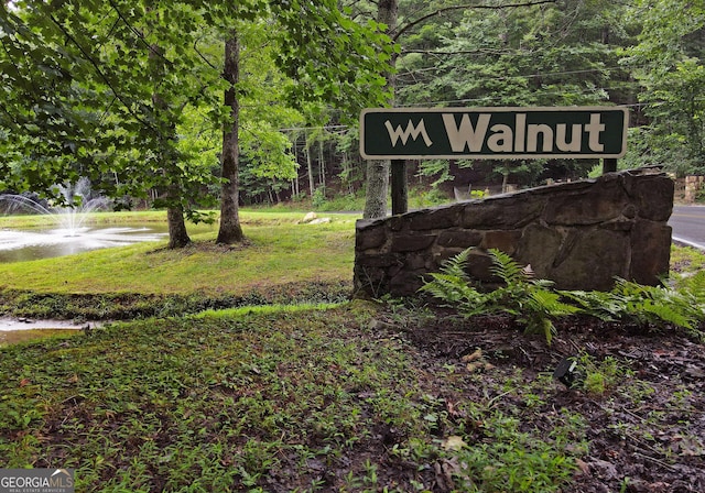 community sign featuring a lawn and a water view