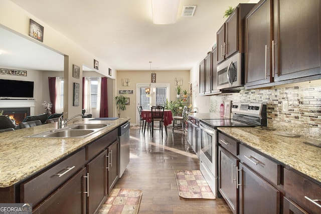 kitchen featuring a sink, decorative backsplash, stainless steel appliances, and dark brown cabinets